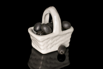 Lot of whole canned black olive in porcelain basket isolated on black glass