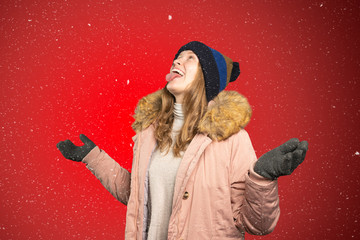 young woman tries to catch snowflakes with her mouth