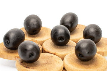 Group of seven whole canned black olive on tree stump isolated on white background