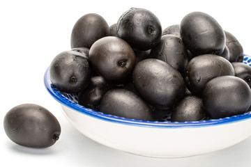 Lot of whole canned black olive on porcelain saucer isolated on white background