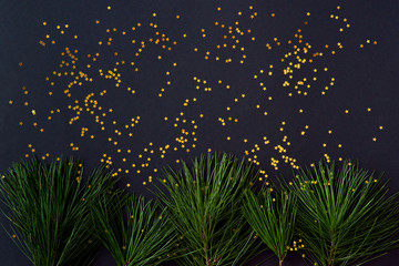 Fototapeta na wymiar Flat lay christmas border with pine branches and golden confetti on a dark background