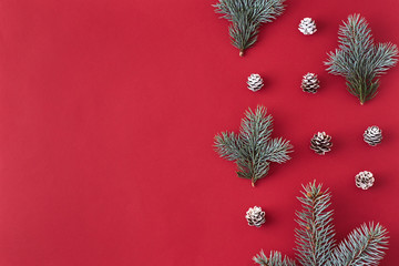 Flat lay christmas border with branches spruce and cones on a red background
