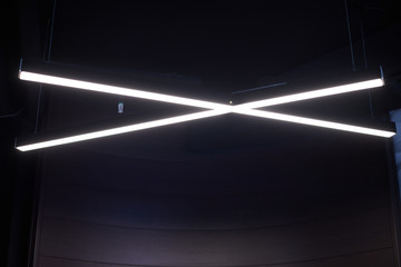 Modern office lighting. Thin lamps in office dark ceiling. LED white cold light over workplaces.