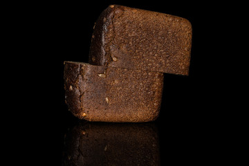 Group of two halves of fresh baked dark bread loaf isolated on black glass