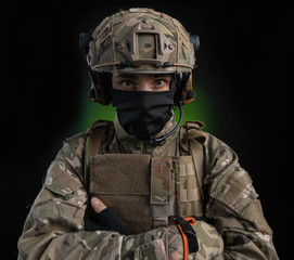 a male soldier in military clothes with a weapon on a dark background
