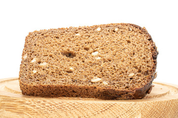 One slice of fresh baked dark bread on bamboo plate isolated on white background