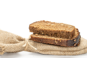 Group of two slices of fresh baked dark bread with jute bag isolated on white background
