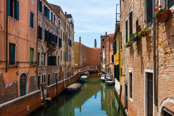 Fototapeta na wymiar Grand Canal in Venice with boats and gandules docket motor boat near the bridge. Colorful residential house and small bridges cross the canal.