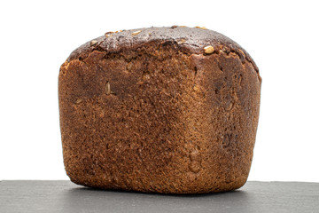 One whole fresh baked dark bread on grey stone isolated on white background