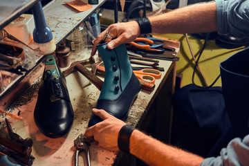 Experienced shoemaker is creating retro leather shoes at his comfortable workshop. - Powered by Adobe