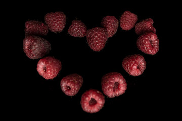 Lot of whole fresh crimson raspberry isolated on black glass