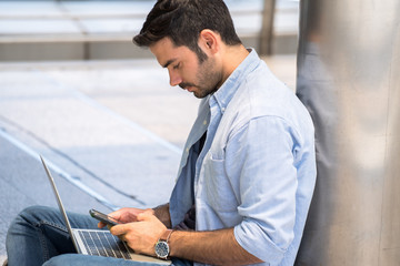 A young business man sitting and chatting with a customer via smartphone.