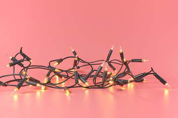 Christmas bright lights garland on a pink background with copy space.