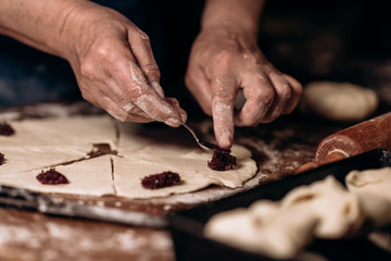 Fototapeta na wymiar Housewife roll pieces of dough with plum jam