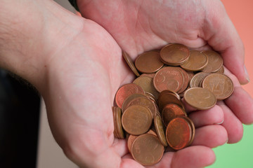 two hands holding a lot of five cent coins