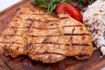 Grilled chicken fillet, steak on wooden board. Close up