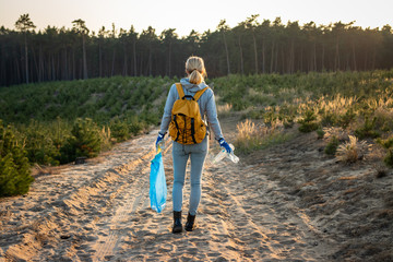 Environmental volunteer. Woman holding plastic waste and garbage bag in forest. Keep nature without plastic pollution!