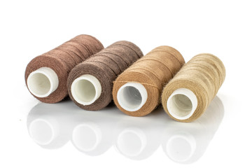 Group of four whole haberdashery item thread spools in row isolated on white background