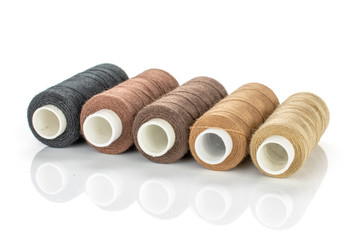 Group of five whole haberdashery item thread spools in row isolated on white background