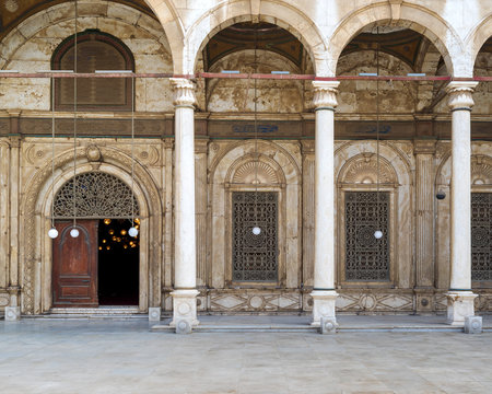 Wrought iron decorated Windows and wooden ornate door over white alabaster decorated wall leading to Mosque of Muhammad Ali Pasha - Alabaster Mosque - Citadel of Cairo, Egypt