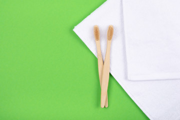 Top view of bamboo toothbrushes on white towels over green background. Flat Lay. Zero waste eco life concept. Plastic free. Place for text.