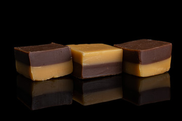 Group of three whole sweet brown caramel chocolate candy in row isolated on black glass