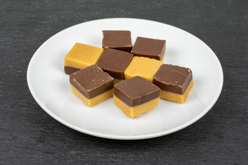 Group of eight whole sweet brown caramel chocolate candy on white ceramic plate on grey stone