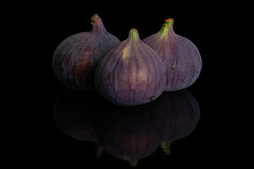 Group of three whole fresh purple fig isolated on black glass
