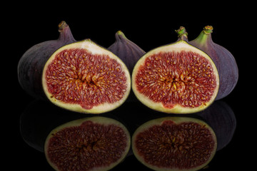Group of three whole two halves of fresh purple fig isolated on black glass