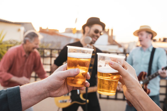 Friends making a toast over their friendship. Young people holding cups of lager beer and cheering for their love. Cold beverage party concept.Happy couple having fun while drinking beer outdoors.