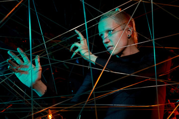 a teenager at a party got tangled up among the ropes. young man in depression in the light of the neon on black background