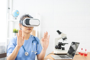 Asian female doctor wearing virtual reality glasses (VR box) testing result with simulator Mixed media futuristic medical interface, Future Innovative technology science medicine Medical concept