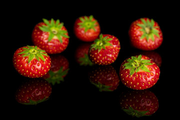 Group of six whole fresh red strawberry isolated on black glass
