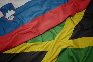 waving colorful flag of jamaica and national flag of slovenia.