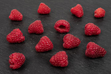 Lot of whole fresh red raspberry on grey stone