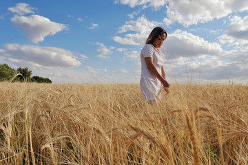 Naklejka na ściany i meble Girl in a white dress. In a wheat field.