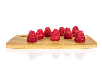 Group of eight whole fresh red raspberry on bamboo cutting board isolated on white background