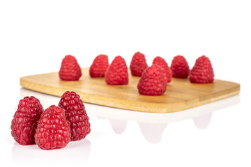 Lot of whole fresh red raspberry on bamboo cutting board isolated on white background