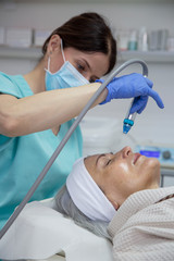 Portrait of middle aged woman having face treatment at beauty clinic