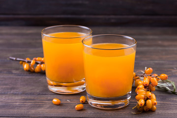 Glass of juice and branches of orange sea buckthorn
