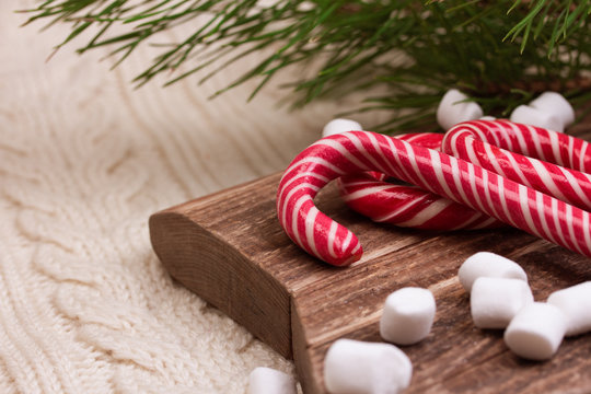 Christmas composition. Spruce branches, candy cane and Marshmallow on a star-shape wooden cutting board.