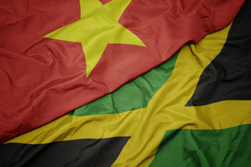 waving colorful flag of jamaica and national flag of vietnam.