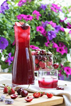 Summer berry cold drink. Iced drink from fresh seasonal berries on bright floral background.