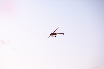 Silhouette of a chopper high in the blue sky seen from below, the military maneuvers; worm’s eye view.