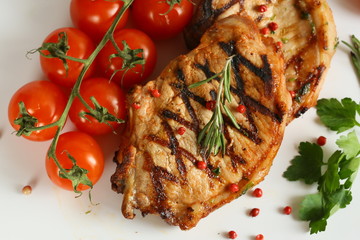 Grilled pork chops with vegetables-cherry tomatoes, peppers, parsley on a wooden Board. Isolate.
