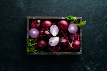 Purple onion in wooden box on black background. Top view. Free copy space.