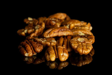 Lot of whole dry brown pecan nut isolated on black glass