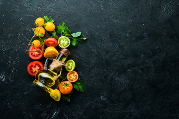 Vegetables. Fresh colored tomatoes On a black stone background. Top view. Free space for your text.