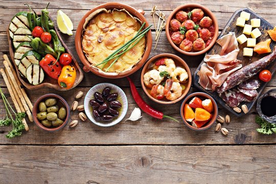 Spanish Tapas. Traditional Mediterranean Appetizer Table Concept Included Tortilla, Grilled Vegetables, Meatballs, Garlic King Prawns,olives And Cured Meat.