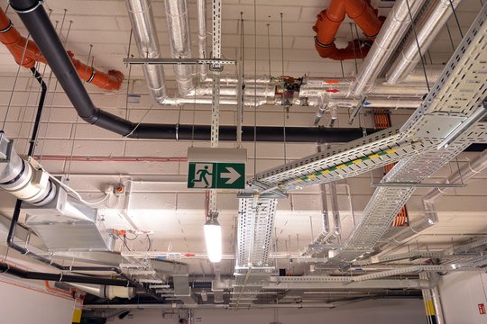 Water pipes and cable trays run under ceiling of a building